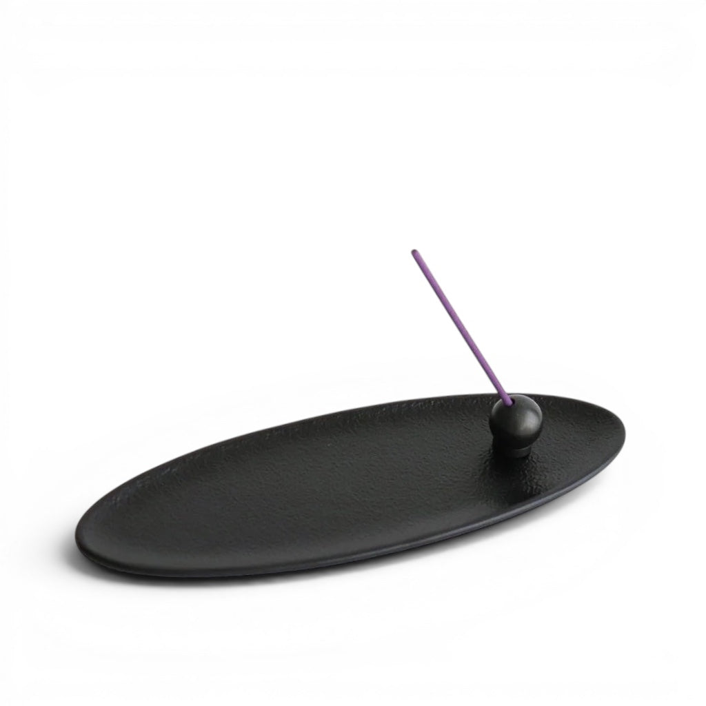 hibino oval black metal incense tray and holder with a purple incense stick on a white background