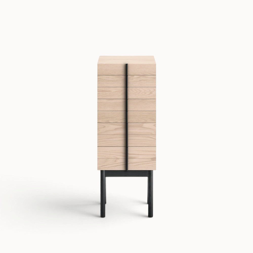 hibino Column Chest in light wood with a vertical black handle detail and elevated black legs on a white background